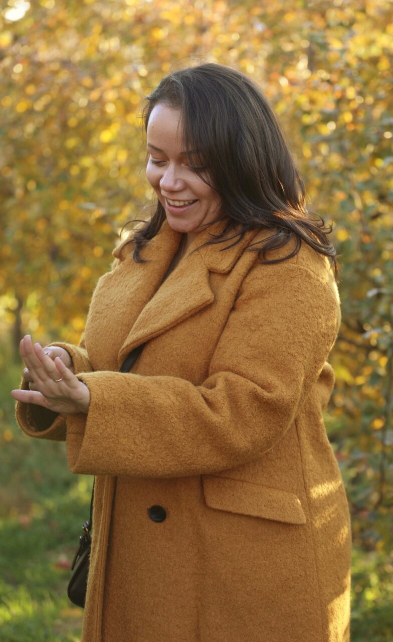 woman in yellow coat wearing a custom frank darling three stone engagement ring