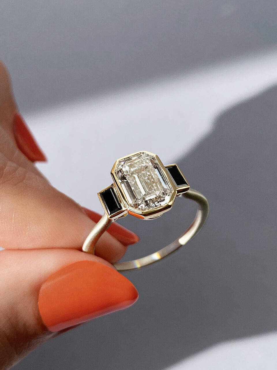 Frank Darling custom emerald cut bezel three stone with black diamond accents.